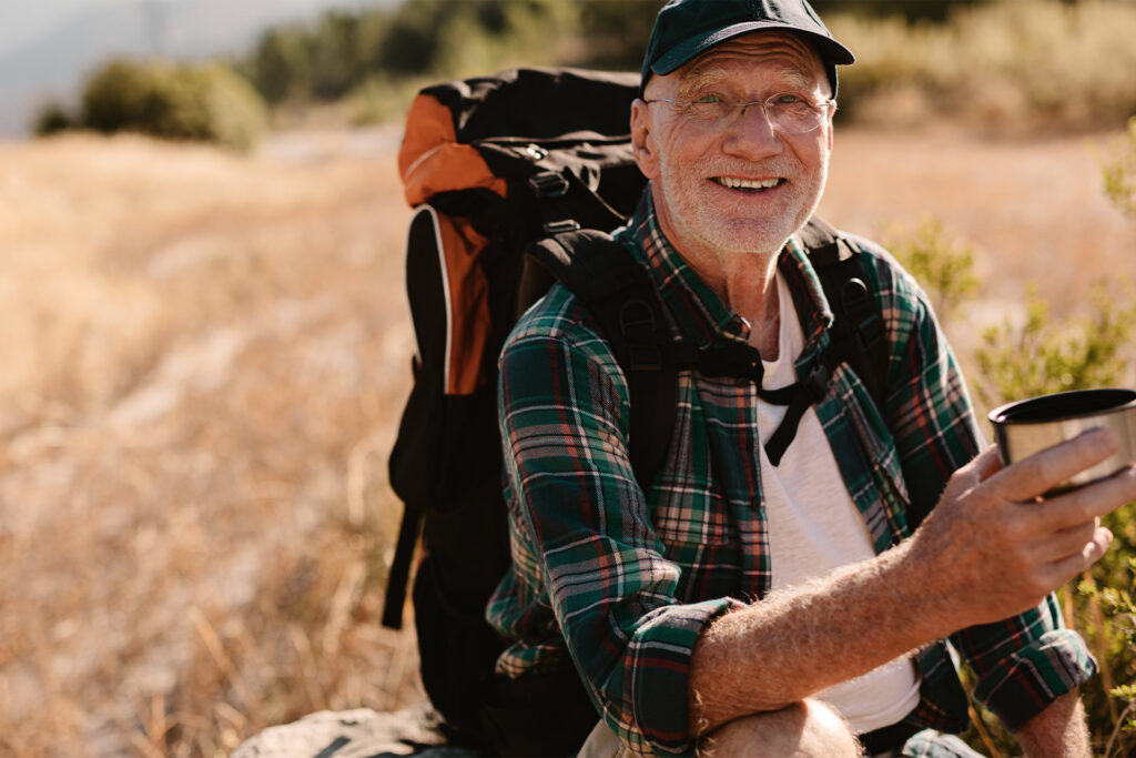 Ældre mand på vandretur i naturen med kaffe