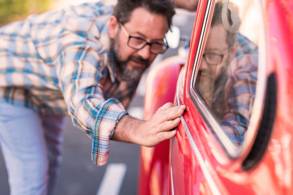 Mand polerer sin røde veteranbil