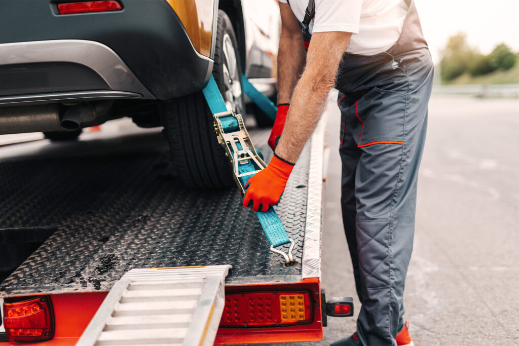 Autohjælp mand spænder bil fast på ladvogn