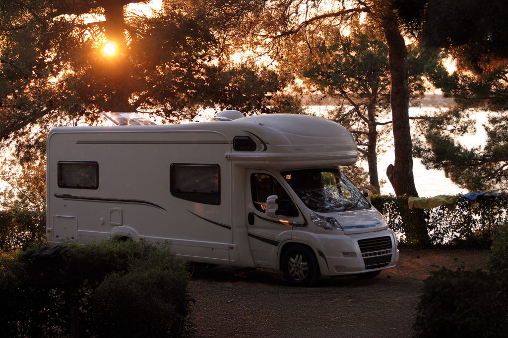 Autocamper i skoven i aftensol